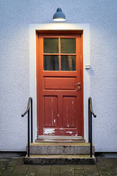 Velho desgastado vermelho pintado porta de madeira com escadas de concreto na frente dele — Fotografia de Stock