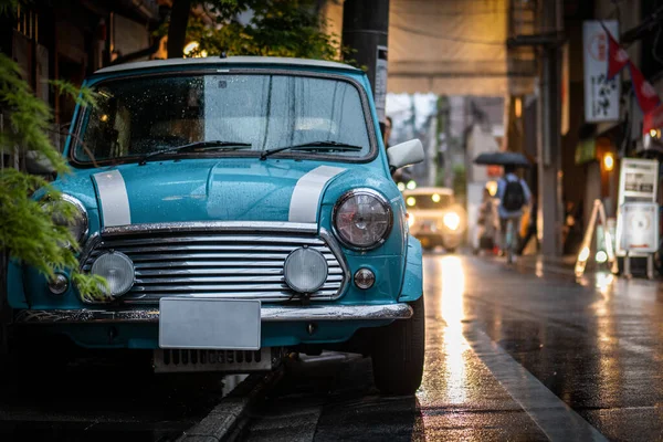 Small blue and white car parked at the rainy street in Japan — Stock Fotó