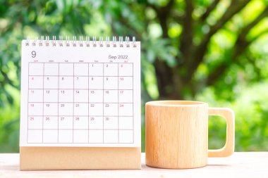 Eylül ayında, Takvim masası 2022 planlama ve ahşap kahve fincanı yeşil doğa arka planlı ahşap masa üzerinde.