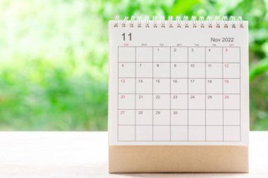 Kasım ayı, Takvim masası 2022 planlama ve hatırlatma için ahşap masa üzerinde yeşil doğa arka planı ile.
