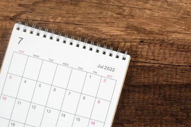 Üst görünüm takvim masası 2022, takvim planlama Temmuz ayında ahşap masa arkaplanı. İş planlama randevusu konsepti