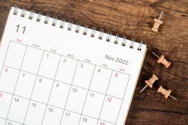Top view Takvim masası 2022 Kasım 'da, ahşap masa zemininde raptiyeli planlama ve teslim tarihi konsepti. İş planlama randevusu konsepti