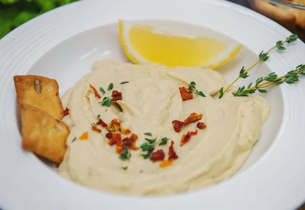 Limon dilimli beyaz tabak humus baharatlı baharatlı baharat ve iki kraker.