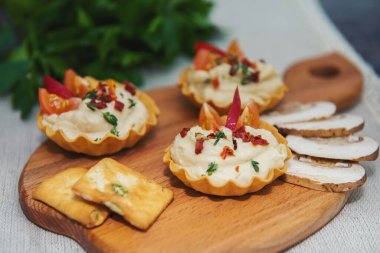 Kesme tahtasındaki gri arkaplanda üç tortelet domates dilimleri ve baharatlı baharat, mantar dilimleri ve krakerler arka planda yan yana uzanmış yeşil 