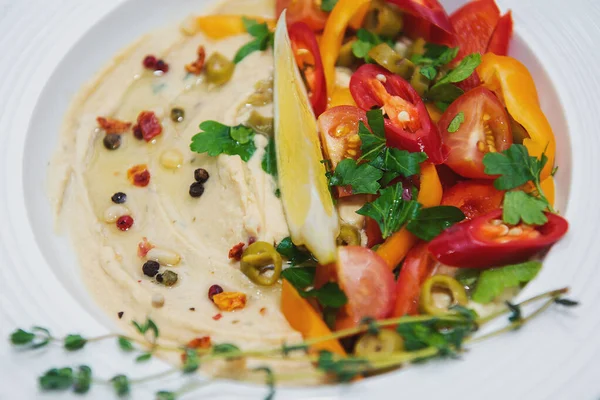 Bir dilim limon dilimlenmiş acı biber dilimleri ve baharatlı baharatlı baharatlı sebzeli sebzeli humus.