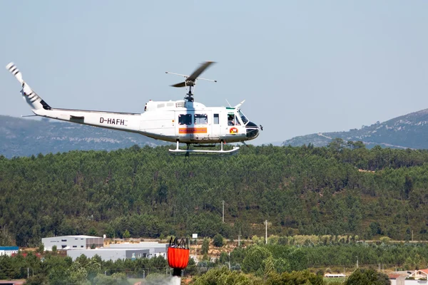 ПОМБАЛ, ПОРТУГАЛЬ - 25 июля: Пожарно-спасательный тяжелый вертолет, с ведром для воды, сброс воды на огонь в Помбале 25 июля 2010 года в Помбале, ПОРТУГАЛЬ — стоковое фото