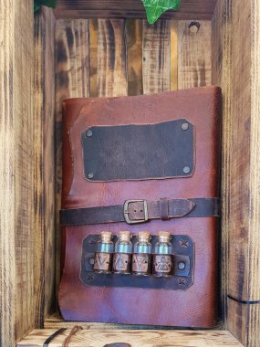 Ahşap bir kutudan yapılmış, deri kapaklı el yapımı bir defterin ön planında dikey bir görünüm. Geri dönüştürülmüş malzeme kullanan deri uçaklar