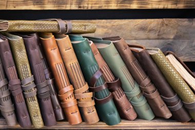 Kitap raflarında ahşap kutulardan yapılmış deri kapaklı el yapımı defterlerin yatay görünümü. Geri dönüştürülmüş malzeme kullanan deri uçaklar