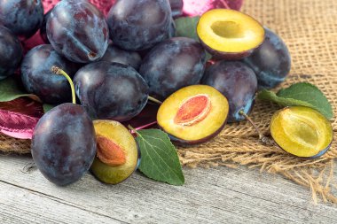 Taze erikler ve ahşap masa üzerinde yeşil yapraklar. Kırsal arkaplandaki erikler.