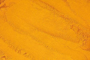 Arka plan ve doku olarak zerdeçal tozu yığını, üst görünüm.