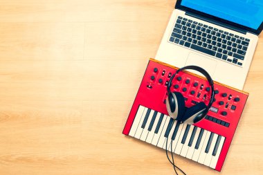 müzik klavyesi, dizüstü bilgisayar ve ahşap masada kulaklık. çevrimiçi müzik e-öğrenimi, müzik üretimi, ev stüdyosu arka plan konsepti