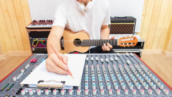 男性专业作曲家喜欢在白纸上创作流行歌曲 同时在录音室里弹奏吉他 创作概念 — 图库照片
