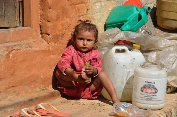 Bhaktapur, nepal, mała dziewczynka gra u progu jej domu obok kosza budowlane. — Zdjęcie stockowe