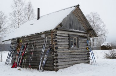 Arkhangelsk region, ski trip, skies lean to a wall of wooden houses during a halt clipart