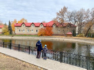        Ufa, Bashkortostan Cumhuriyeti, Rusya, 17 Ekim 2021: Baba ve oğlu, S.T. adını verdikleri bahçedeki göletin kıyısında duruyorlar. Sonbaharda Aksakov. Ufa, Bashkortostan Cumhuriyeti