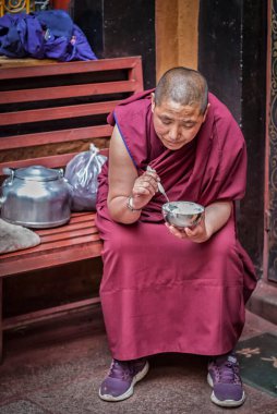 LHASA, TIBET, ÇİN - 17 AĞUSTOS, 17 2018: Ani Sangkhung Nunnery 'de yemek yiyen tanımlanamayan rahibe. Ani Sangkhung Nunnery, Tibet 'in en eski aktif manastırlarından biridir..  