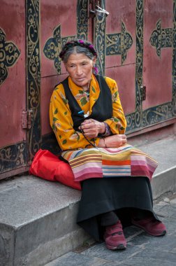 LHASA, Tibet, Çin - 17 Ağustos 2018: Geleneksel giysiler içinde yaşlı Tibetliler Jokhang Tapınağı yakınlarındaki bir bankta oturuyorlar 