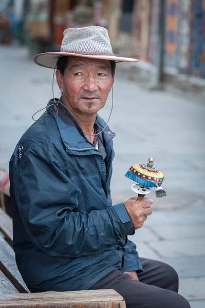 2018年8月17日 中国台伯市Lhasa 一名身穿传统服装的身份不明的西藏男子坐在附近的长椅上 手持祈祷轮祈祷 — 图库照片