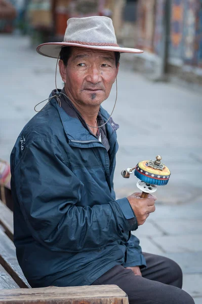 2018年8月17日 中国台伯市Lhasa 一名身穿传统服装的身份不明的西藏男子坐在附近的长椅上 手持祈祷轮祈祷 — 图库照片