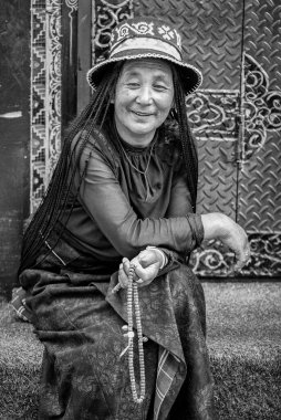LHASA, TIBET, ÇİN - 18 Ağustos 2018: Geleneksel giysiler içinde tanımlanamayan Tibet hacısı Jokhang tapınağının yanında Tibet malası ile oturuyor 