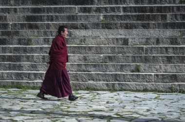 Tibet, Çin - 19 Ağustos 2018: Drepung Manastırı 'nda yürüyen Tibetli keşiş. Tibet manastırlarının en büyüğüdür ve Gephel Dağı 'nın eteğindeki Gambo Utse dağında yer alır. Tibet