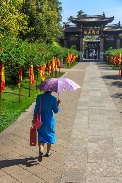 Woman with umbrella walking in temple complex — Stock Photo, Image