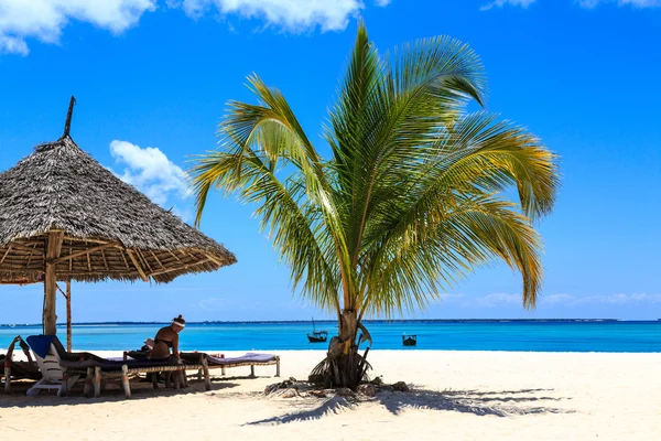 Frau sitzt an einem tropischen Strand Stockfoto