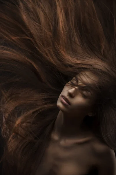 Vacker kvinna med långt hår på mörk bakgrund — Stockfoto