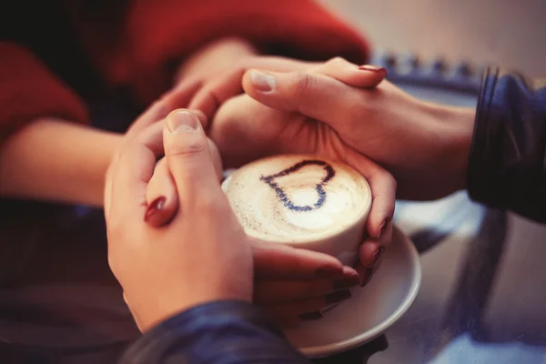 Quatre mains enroulées autour d'une tasse — Photo