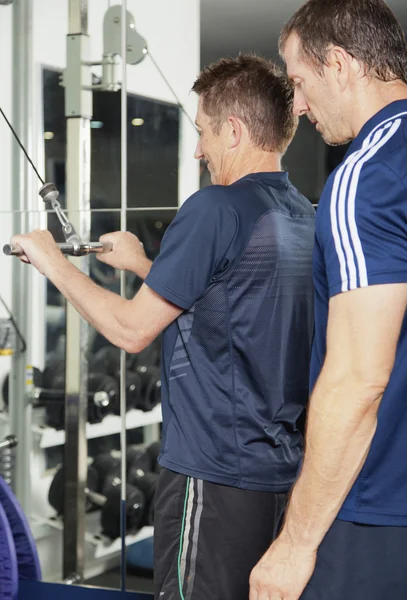 Hombre mayor y PT en el gimnasio — Foto de Stock