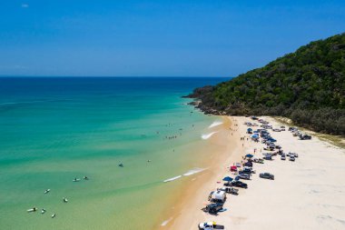 Güneşli bir günde, Double Island Point, Queensland Avustralya 'da 4WD araçları ve sörfçüler