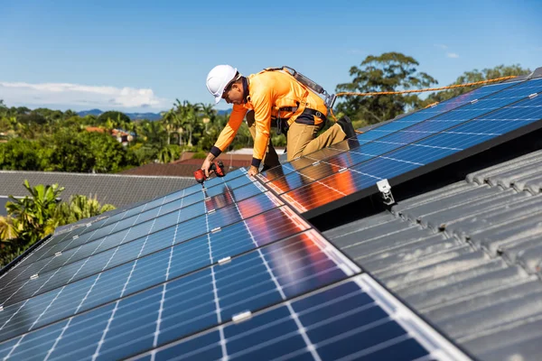 阳光充足时 太阳能电池板技术员在房顶上安装太阳能电池板 图库照片