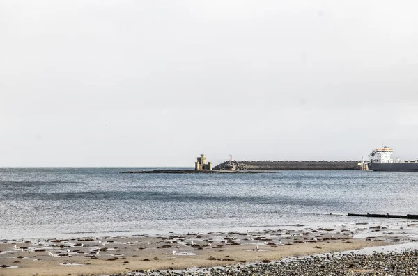 马恩岛道格拉斯湾海滩与圣玛丽岛的庇护所塔保持距离 免版税图库图片