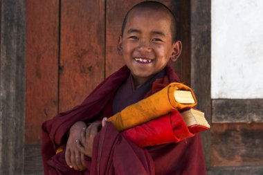 Little Buddhist monk with prayer books in Bhutan clipart