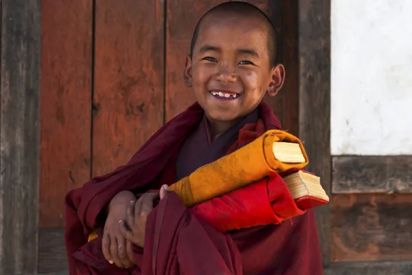 Piccolo monaco buddista con libri di preghiere in Bhutan — Foto Stock