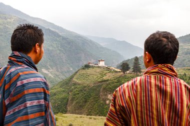 Bir gho (Bhutanese geleneksel giysileri) içinde iki adam Bhutan, Asya 'nın merkezinde eski bir manastıra bakar.