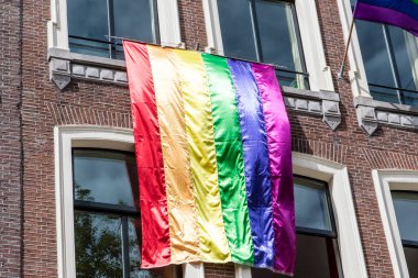 Amsterdam, Hollanda ve Avrupa 'nın tarihi merkezinde Gay Pride sırasında eski bir Hollanda binasının solgunluğunda gökkuşağı bayrağı