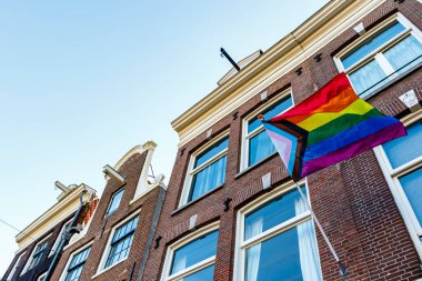 Old Dutch canal houses in Amsterdam with a Progress Pride Flag on their facades during Gay Pride Amsterdam, The Netherlands, Europe