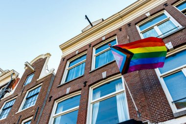 Old Dutch canal houses in Amsterdam with a Progress Pride Flag on their facades during Gay Pride Amsterdam, The Netherlands, Europe