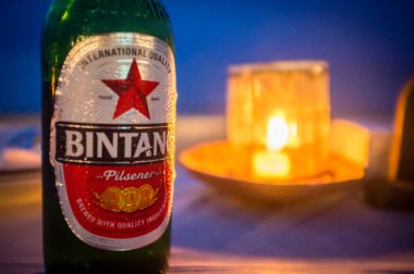 Bintang bira şişesi ve Endonezya 'nın Bali sahilinde mum ışığı.