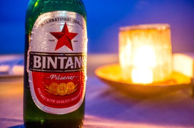 Bintang bira şişesi ve Endonezya 'nın Bali sahilinde mum ışığı.