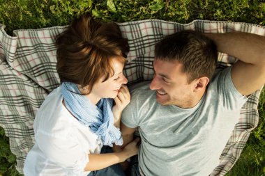 gülümseyen genç bir çift bir parkta yalan