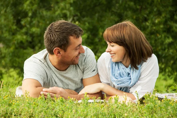 Sonriente pareja y acostado en la hierba al aire libre —  Fotos de Stock