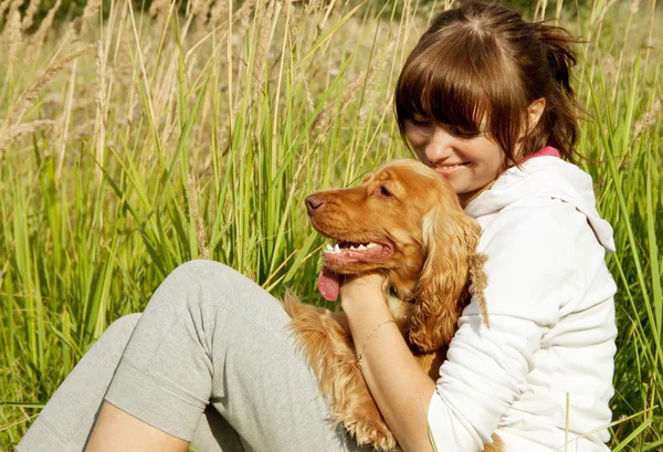 Boldog fiatal lány kutyájával a füvön átfogó — Stock Fotó