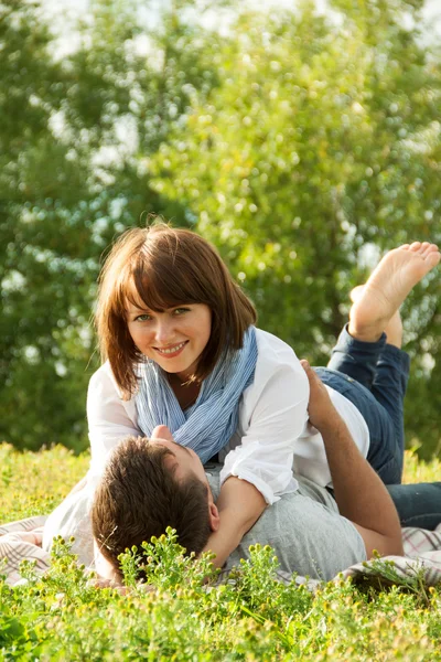 Ungt par fastställande i gräset och kramar varandra — Stockfoto