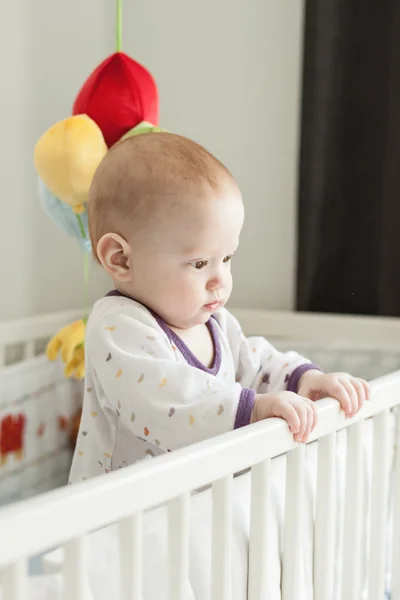 Младенец, стоящий в детской кроватке — стоковое фото