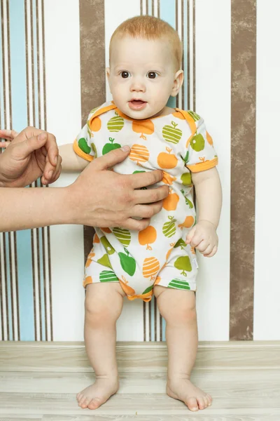 O bebê está de pé com ajuda — Fotografia de Stock