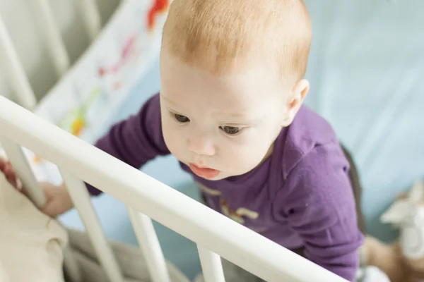 Baby boy trying to stand up in his cot — Stock Photo, Image