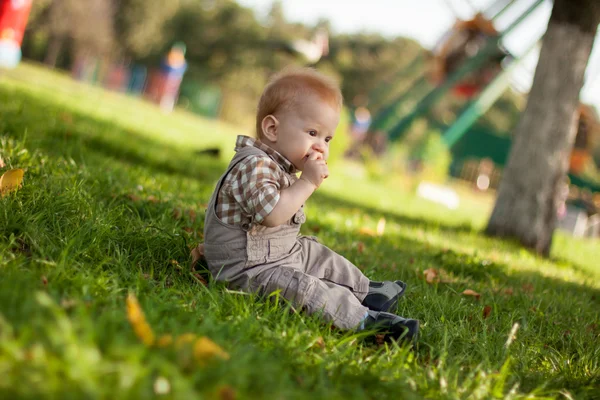 Bebê bonito sentado em uma grama — Fotografia de Stock