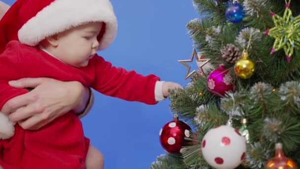 Mutter mit Baby schmückt Weihnachtsbaum mit schönen Ornamenten. — Stockvideo